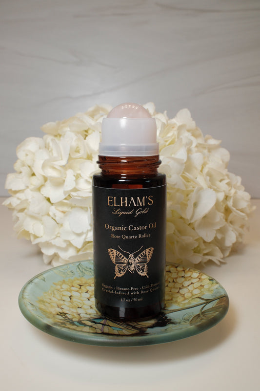 Elham’s Organic Castor Oil Rose Quartz Roll-On beside white hydrangeas