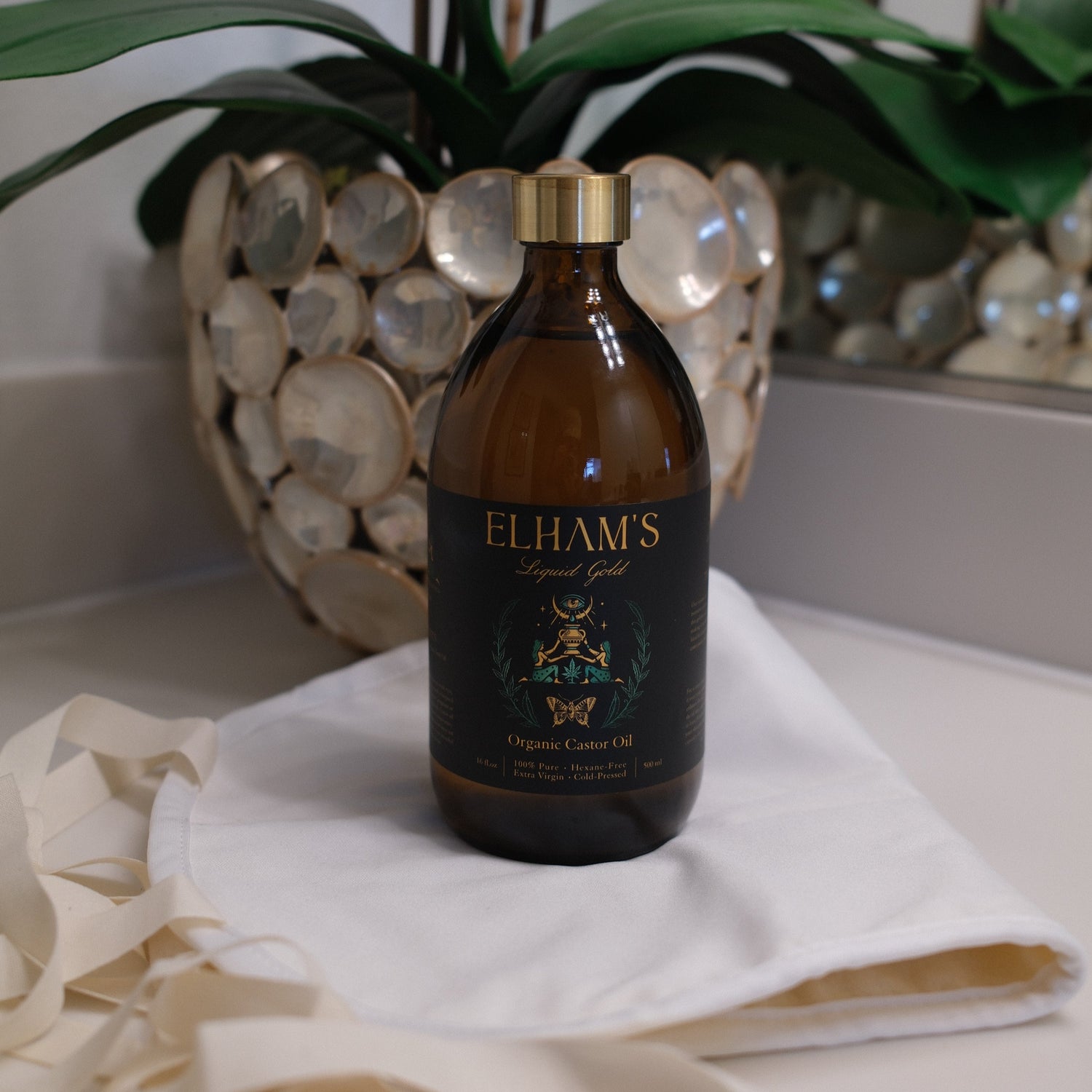 Bottle of castor oil sitting on an organic cotton pack on a vanity table