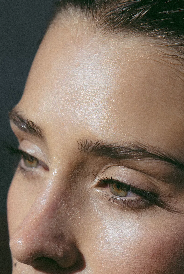 closeup photo of a woman's face, showing her forehead, eyes, and nose. She looks moisturized
