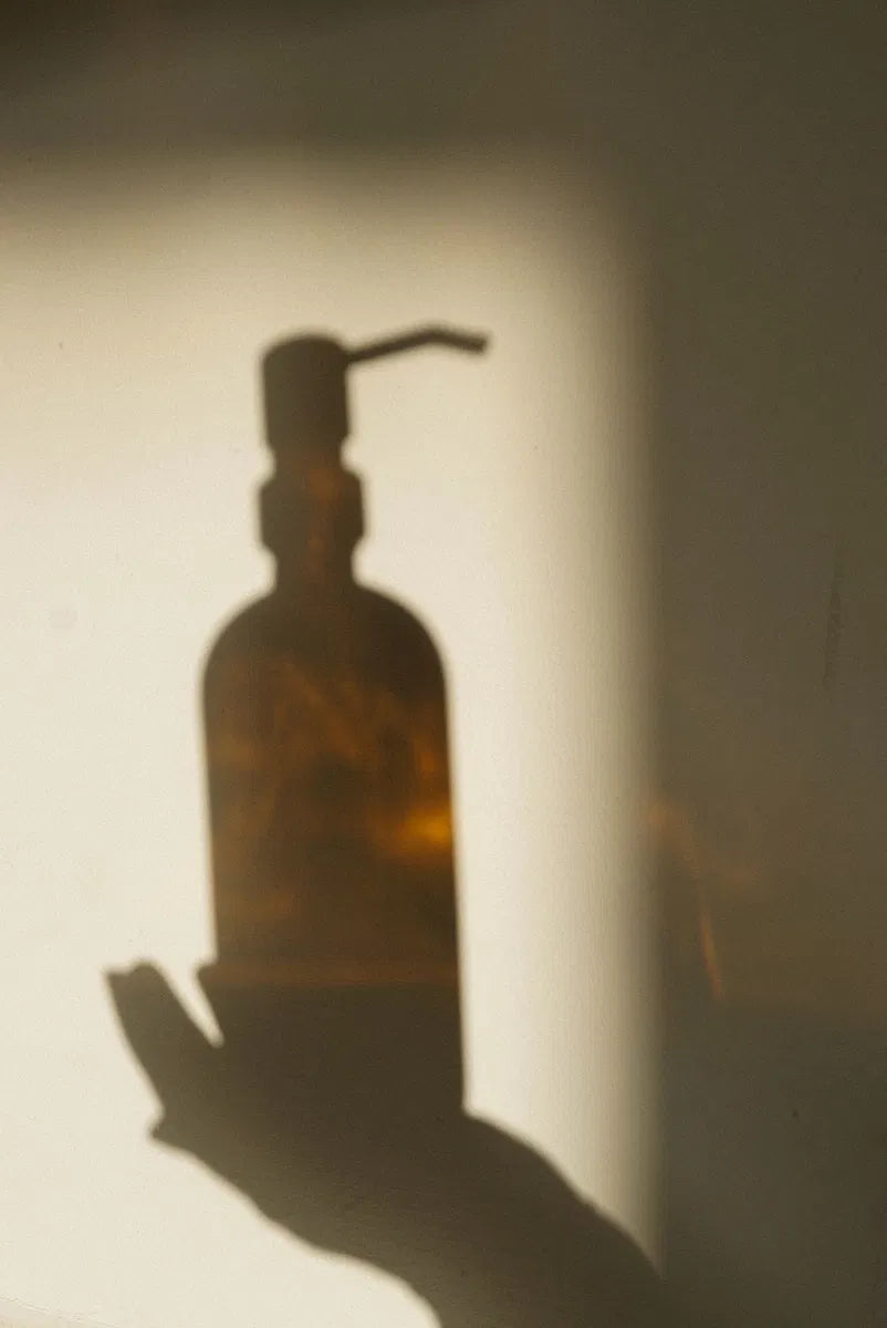 Shadow of a bottle of castor oil held by a female hand