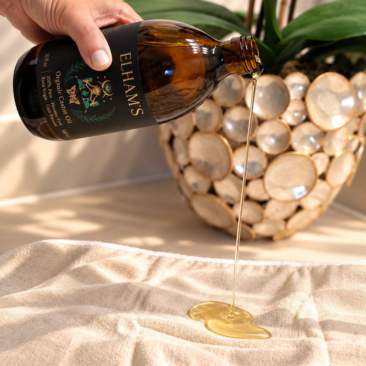 Elham's organic castor oil poured from an amber glass bottle onto an organic cotton castor oil pack