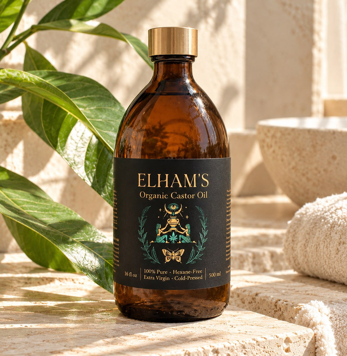 Elham's Organic Castor Oil in an amber glass bottle with a gold cap, in warm sunlight beside green leaves